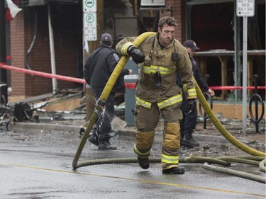A fireman carries a fire-hose past the remains of the Beaver's Mug Cafe and Silver Scissors Hair salon after a structure fire that ultimately spread to the neighbouring Pizza Hut, Mac's corner store and the Encino Taco shop at 11pm on Thursday, April 9.