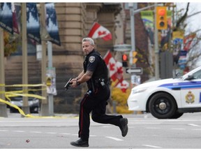 An Ottawa police officer runs with his weapon drawn in Ottawa on Wednesday Oct.22, 2014.