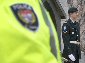 An Ottawa Police officer stands watch over the ceremonial guards at the National War Memorial Wednesday April 22, 2015.