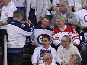 A fan takes a photo of Sheldon Kennedy and Prime Minister Stephen Harper during a break in third period action in Game Four of the Western Conference Quarterfinals between the Anaheim Ducks and Winnipeg Jets Wednesday night.