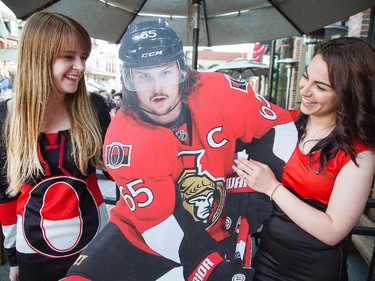 Andrea Laarakkers (L) and Yasmine Pourseyed with a cut out of Erik Karlsson at the Sens House as Sens fans pour onto the Sens Mile along Elgin St and the Sens Square in Byward Market to watch Friday's game between Montreal Canadiens and Ottawa Senators being played in Montreal.