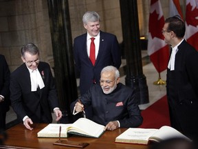 India's Prime Minister Narendra Modi signs a visitors book in Parliament Hill as Canada's Prime Minister Stephen Harper looks on behind, during a welcome ceremony in Ottawa, Canada on April 15, 2015.AFP PHOTO/ COLE BURSTONCole Burston/AFP/Getty Images
