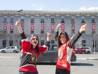Christine Gauthier, left, and Dana Diab cheer on their team Friday night to the backdrop of banners installed by McMillan creative agency at its offices on George Street. Sens fans were out in force at the Sens Mile on Elgin Street and the ByWard Market's Sens Square as the Senators played the Canadiens in Montreal, ultimately losing in overtime.