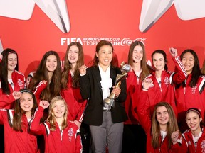 Current FIFA World Cup Winner, Japan's Nozomi Yamago, poses with the coveted trophy and with local soccer players from the Nepean Hotspurs. Tickets for the FIFA Women's World Cup quarterfinal in Ottawa are 85 per cent sold.