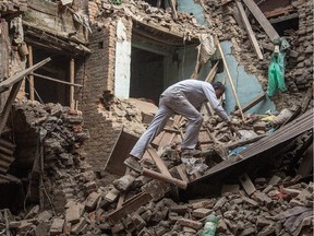 A man climbs on top of debris after buildings collapsed on Sunday in Bhaktapur, Nepal. A major 7.8 earthquake hit Kathmandu mid-day on Saturday, and was followed by multiple aftershocks that triggered avalanches on Mt. Everest that buried mountain climbers in their base camps.