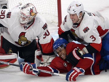 Montreal Canadiens right wing Devante Smith-Pelly (21) is knocked to the ice by Ottawa Senators defenseman Marc Methot (3) in front of Ottawa Senators goalie Andrew Hammond (30) during third period of Game 2 NHL first round playoff hockey action Friday, April 17, 2015 in Montreal.