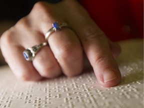 Diane Bergeron a sight-impaired executive with the CNIB, reads from a braille book in the Ottawa office on Tuesday.