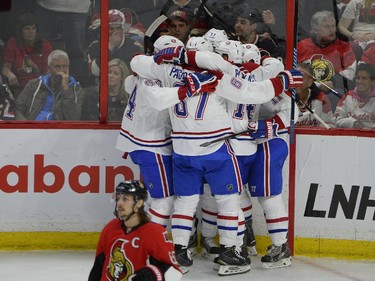 The Montreal Canadiens celebrate a first period goal by Brendan Gallagher (11) as Ottawa Senators' Erik Karlsson (65) looks on during the first period of an NHL Stanley Cup playoff hockey game, Sunday April 26, 2015, in Ottawa.