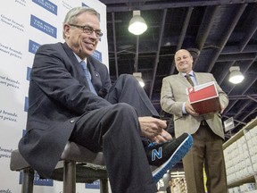 Federal Finance Minister Joe Oliver tries on his new budget shoes with the assistance of Bruce Dinan, president of Town Shoes, during a photo op in Toronto on Monday, April 20, 2015.