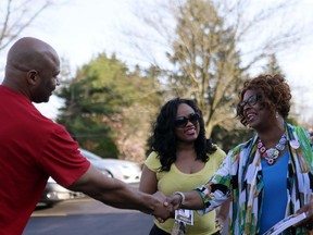 Ferguson City Council candidate Ella Jones, right, greets Victor, left, and Aleshia Jordan as they come to vote at St. Peter's United Church of Christ in Ferguson, Mo., Tuesday, April 7, 2015. Voters braved heavy rain and lightning to get to the polls for municipal elections in Ferguson that could substantially boost the number of African-American city council members in the St. Louis suburb at the center of a national debate about how police interact with black residents.