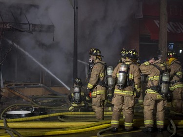 Firefighters attempt to control a structure fire at the Beaver's Mug cafe and Silver Scissors Hair  in the Glebe on Bank Street in Ottawa on Thursday, April 9, 2015