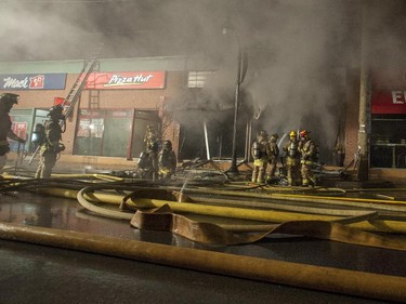 Firefighters attempt to control a structure fire at the Beaver's Mug cafe and Silver Scissors Hair in the Glebe on Bank Street in Ottawa on Thursday.