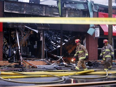 Firefighters walk past a commercial building destroyed by fire on Bank St. near Fifth Ave. in Ottawa, Friday, April 10, 2015.