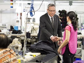 Finance Minister Joe Oliver, centre, greets employees at Canada Goose, where he announced the date of the federal budget, in Toronto on Thursday.