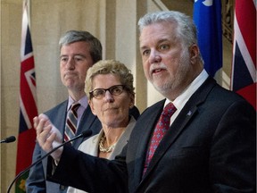 Quebec Premier Philippe Couillard, right, speaks at a news conference following a meeting with Ontario Premier Kathleen Wynne (centre) Monday, April 13, 2015 at the premier's office in Quebec City. Ontario Environment Minister Glen Murray looks on at left.