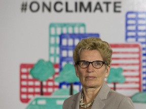 Ontario Premier Kathleen Wynne listens to questions from the media during an announcement which outlined a cap and trade deal with Quebec aimed at curbing green house emissions, in Toronto on Monday, April 13 2015. The plan involves government-imposed limits on emissions from companies, and those that want to burn more fossil fuels can buy carbon credits from those that burn less than they are allowed.