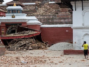 A young man speaks on the phone in front of a collapsed temple in the city center following an earthquake on April 25, 2015 in Kathmandu, Nepal. A major 7.8 earthquake hit Kathmandu mid-day on Saturday, and was followed by multiple aftershocks that triggered avalanches on Mt. Everest that buried mountain climbers in their base camps. Many houses, buildings and temples in the capital were destroyed during the earthquake, leaving hundreds dead or trapped under the debris as emergency rescue workers attempt to clear debris and find survivors.