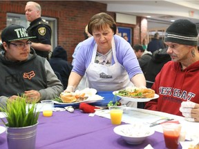 One of the many volunteers, Liga Dekmeiers-Georgopoulos, serves warm plates of food at the Ottawa Mission.  The Mission is serving Easter feasts for anyone in the community who is hungry, homeless, or alone, April 06, 2015.