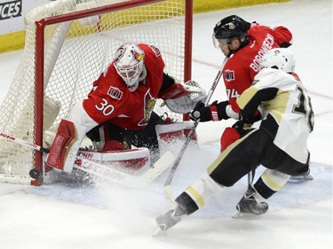 Ottawa Senators' Andrew Hammond (30) makes a save as teammate Mark Borowiecki (74) defends against Pittsburgh Penguins' Brandon Sutter (16) second period NHL action.