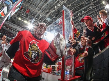 Andrew Hammond #30 of the Ottawa Senators high-fives fans as he leaves the ice after warmup.