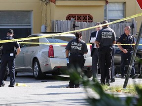 In this photo taken on Monday, March 30, 2015, Miami-Dade police detectives work at a crime scene in Miami, involving the two teenage sons of Roxanne Dube, Canada's counsel general in Miami.