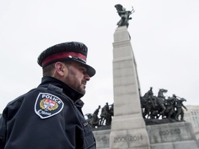 Ottawa Police Const. Santiago De Los Santos watches over the National War Memorial in Ottawa as sentries return to their post for their first day, on Thursday, April 9, 2015. The Department of Defence has hired the Ottawa Police to guard the sentries, after Cpl. Nathan Cirillo, a reservist guarding the Tomb of the Unknown Soldier, was shot and killed by a gunman while on sentry duty on Oct. 22, 2014.
