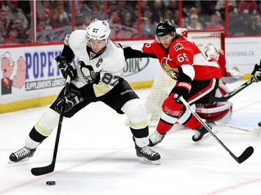 Sidney Crosby looks to make a play while Erik Karlsson defends in the second period.