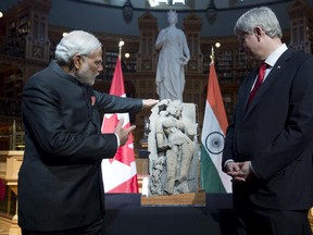 Canadian Prime Minister Stephen Harper returns a sculpture of a woman known as "parrot lady" to Indian Prime Minister Narendra Modi in the Library of Parliament Wednesday.