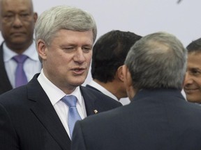 Canadian Prime Minister Stephen Harper speaks briefly with Cuban President Raul Castro as leaders take their places for the official family photo at the Summit of the Americas in Panama City on Saturday April 11, 2015.