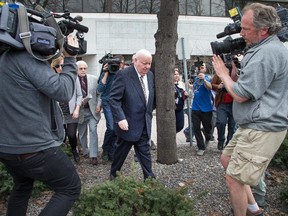 Suspended Sen. Mike Duffy makes his through the bushes and around the media as he heads to a waiting vehicle following the early conclusion of his trial at the Elgin Street Courthouse on April 13, 2015.