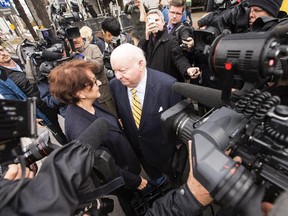 Suspended Senator Mike Duffy, right, and his wife, Heather, are surrounded by cameras and reporters outside the Ottawa Courthouse as they wait for their car Friday April 10, 2015.