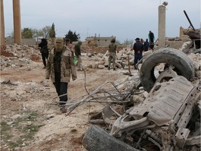 Rebel fighters walk through the rubble following an alleged bombing by Islamic State (ISIL) in northern Aleppo, Syria, on April 8, 2015.