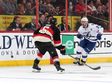 Ryan Callahan #24 of the Tampa Bay Lightning chips the puck past Cody Ceci #5 of the Ottawa Senators.