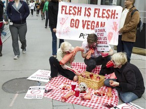 Zombie "undead" PETA supporters at Bank and Albert Sts. picnic on "human limbs" beneath a banner that proclaims, "Flesh Is Flesh: GoVegan," Oct 29.