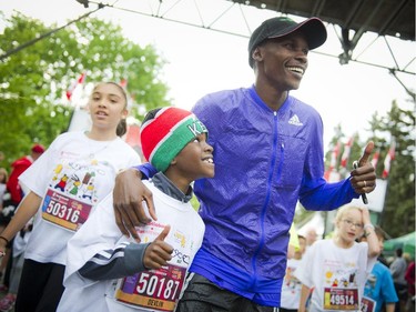 Devlin Taillon, 8, with Kenyan mentor David Kogei, who finished the 10K yesterday in third place at the end of the kids marathon at Tamarack Ottawa Race Weekend, Sunday, May 24, 2015.