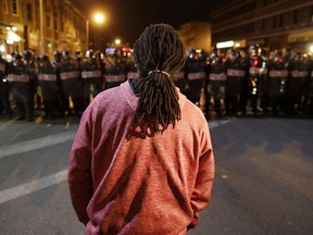 A protester watches as police enforce curfew for the third night, Thursday, April 30, 2015, in Baltimore.