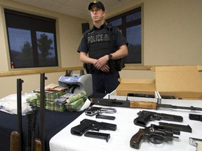 An OPP officer stands by some of the guns, drugs and money seized in this file photo. Local police are offering a gun amnesty next month.