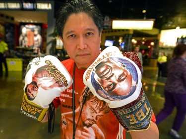 Boxing fan Daniel De Jesus poses in boxing gloves decorated with photos of Manny Pacquiao and Floyd Mayweather which he bought at a merchandise store,  in the MGM Grand Hotel, May 1, 2015.  Mayweather and Pacquiao will meet in the ring on May 2, 2015 at the MGM Grand Garden Arena.