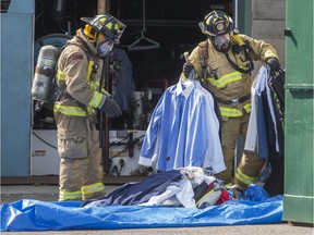 Frefighters shift dry cleaning at Brown's Cleaners on City Centre Avenue, where a fire broke out Saturday, May 2, 2015.