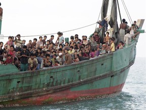 In this Wednesday, May 20, 2015 photo, migrants sit on their boat as they wait to be rescued by Acehnese fishermen on the sea off East Aceh, Indonesia. Many of the thousands of migrants abandoned at sea in Southeast Asia this month are Rohingya Muslims who fled their home country of Burma.