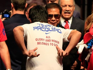 Manny Pacquiao points to the back of his shirt reading 'All Glory And Honor Belong To God' during his official weigh-in on May 1, 2015 at MGM Grand Garden Arena in Las Vegas, Nevada. Pacquiao will face Floyd Mayweather Jr. in a welterweight unification bout on May 2, 2015 in Las Vegas.