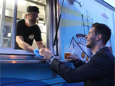From left, Mario Burke of Ad Mare serves crab cakes on a bun to Chris Boerger from his mobile restaurant at the Ottawa Riverkeeper Gala held Wednesday, May 27, 2015, at Albert Island on the Ottawa River.