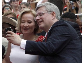 Prime Minister Stephen Harper and his wife Laureen take a "selfie" while their son Ben looks on during Canada Day celebrations on Parliament Hill in Ottawa, Tuesday, July 1, 2014. When the prime minister says the government's new tax package will benefit all Canadian families with children under 18, will that include his own? Stephen Harper isn't saying.