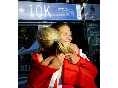 Lanni Marchant gives fellow runner Natasha Wodak, both of Canada, a big hug at the 10K finish line.