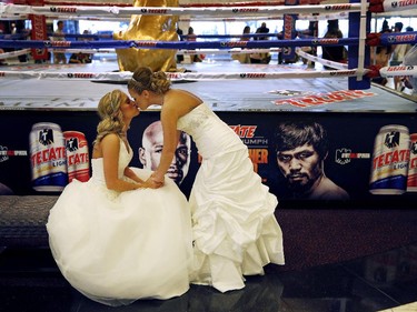 Marcey Wood, right, kisses wife Elizabeth Wood in the lobby of the MGM Grand, after their wedding Friday, April 24, 2015, in Las Vegas. Behind them are advertisements for a fight between Floyd Mayweather Jr. and Manny Pacquiao which is scheduled to take place May 2 at the hotel and casino.