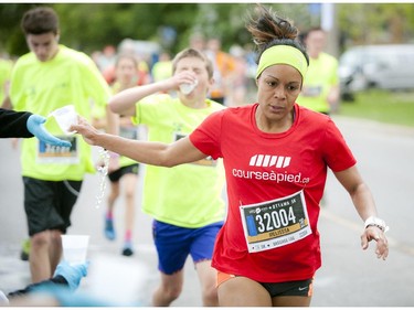 Melisssa Lesage grabs some water in the last stretch of the 5K run at Tamarack Ottawa Race Weekend Saturday May 23, 2015.