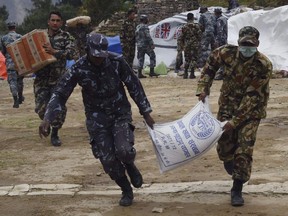 Nepali soldiers and policemen run with parcels of food aid unloaded from a Chinese helicopter during relief operations in the north-central village of Nepal.