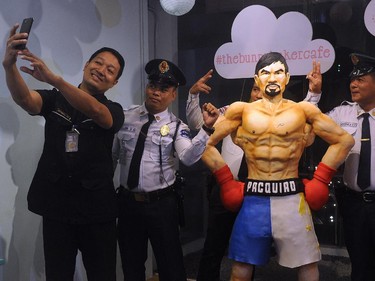 Security guards take a selfie with a life size 70 kilogram cake worth 4000 USD of Philippine boxing icon Manny Pacquiao at a cafe in Manila on May 2, 2015. The cake was made to commemorate the upcoming fight between Pacquiao, considered a national icon, and his rival American Floyd Mayweather and will be shown live on May 3 at the store. If Pacquiao wins the cake will be served free to customers.