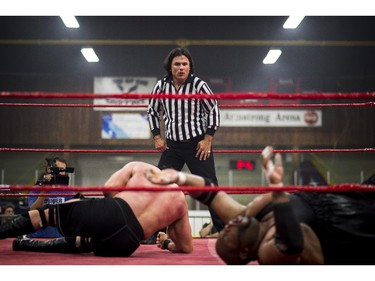 Patrick Brazeau looks concerned as wrestlers Hannibal, left, and Soa Amin, right, continue the match.