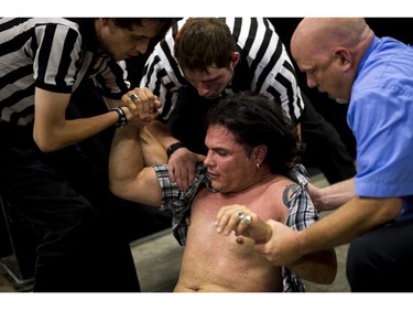 Other referees help suspended senator Patrick Brazeau up after he was body slammed by pro wrestler Hannibal.